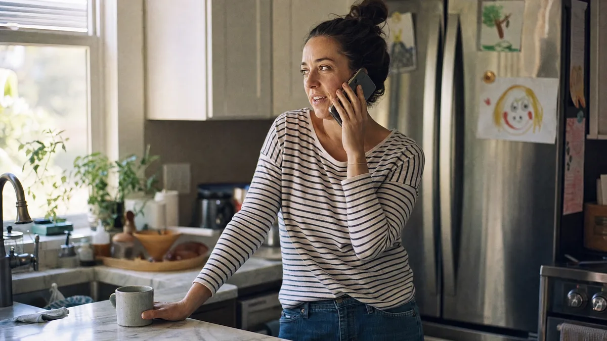 Una madre habla por teléfono con el equipo de DDE en la mesa de su cocina.